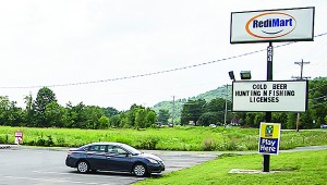 Photo by Brandon Hicks Tom "Yogi" Bowers, chairman of the Carter County Beer Board, said the presence of a convenience store that sells beer, in the foreground, won't impact the proposed construction of a new middle school, on land in the background.