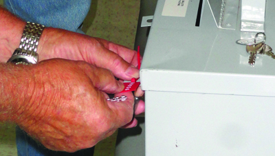 Photo by Abby Morris-Frye Election officials have begun preparations for the upcoming November election. Here members are seen locking and sealing the boxes that will hold absentee and provisional ballots.