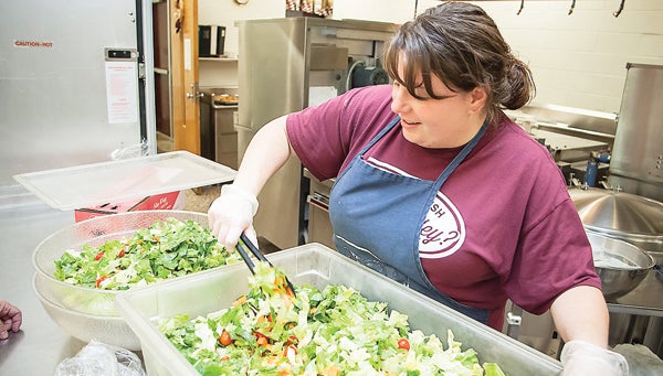 Photo by Brandon Hicks Crystal Roark, a cook at Happy Valley Middle School, prepares a salad for lunch on Friday.