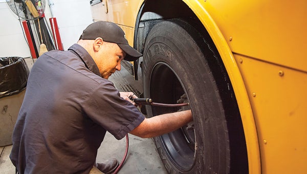 Photo by Brandon Hicks Jonathan Bowers, shop foreman at the Carter County school bus garage, checks tire pressure during a routine safety inspection on one of the buses in the system’s transportation fleet. (For more photos visit www.elizabethton.com)