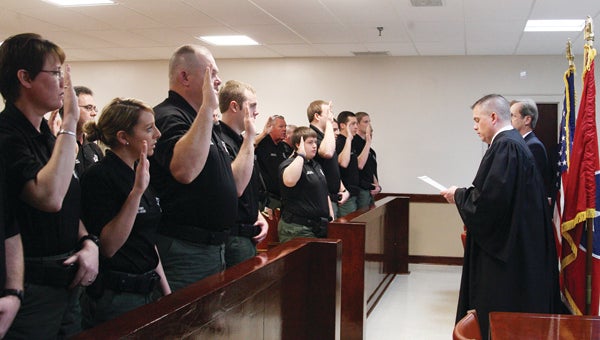 Photo by Abby Morris-Frye Judge Keith Bowers, at right, administers the oath of office to Sheriff's Department employees.
