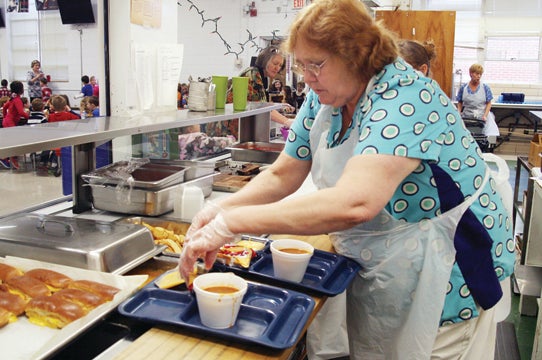 Photo by Abby Morris-Frye Diane Nave prepares trays for students at Hunter Elementary School.