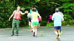 Star Photo/Abby Morris-Frye Runners taking part in the Diamond Dash received encouragement and high fives from Roan Mountain State Park Seasonal Interpretive Ranger Joe Nowotarski as they crossed Highway 143 to make their way onto the Raven Rock Trail.