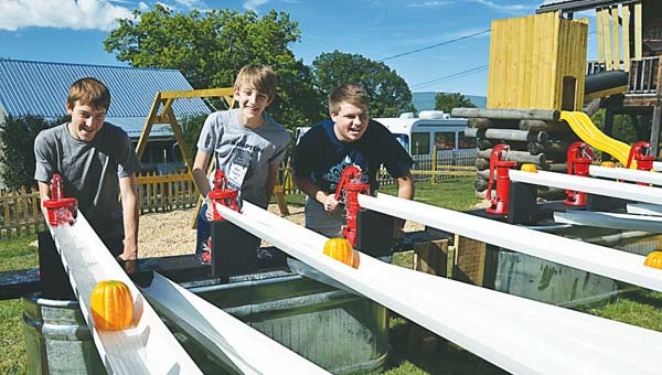 Star Photo/Rebekah Price Blake Gentry (left), son of owners Curtis and Desie Gentry, Matthew Miller (center) and Travis Boggs (right) compete in the pumpkin flume race, in which Boggs championed his opponents, as he promised.
