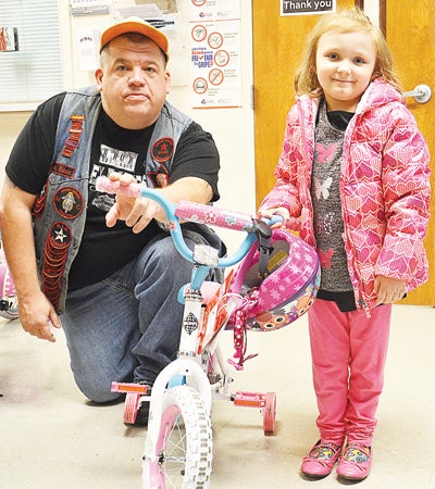 Star Photo/Rebekah Price  An Elizabethton Housing and Development Agency toy drive organizer from the Ghost Riders Motorcycle Club, Lima Bean, presents Anna Stonecipher with her brand new bicycle.