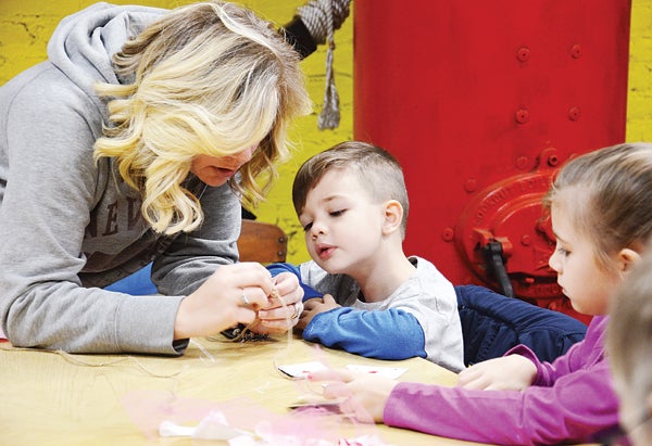 Star Photo/Rebekah Price  Christin Williams and her children Owen and Carmindy string together fabric strips and cards to make a crafty window, door or wall decoration.