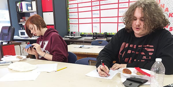 Contributed Photo  Unaka High School students Sarah Hoss and Josh Leavitt measure Little Debbie cakes to see if the diameter and circumference yield the ratio of pi.