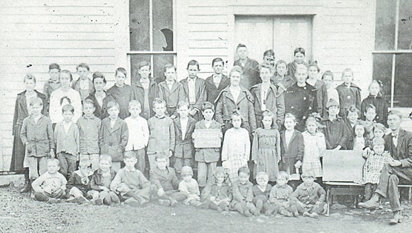 Contributed Photo  This photo was printed on a post card in the 1920s with Educator Joe Taylor pictured with students at his school. Ronnie Taylor, his son, believes this may have been taken at Midway School, and noted the varying ages of the children and the condition of the schoolhouse.