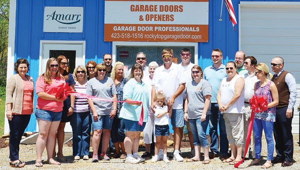 Star Photo/Rebekah Price  Rocky Top Garage Door owners Teresa and Mitch Parlier cut the ribbon announcing the grand opening at their new location on Broad Street. They were joined by friends, family and Elizabethton/Carter County Chamber of Commerce executives.