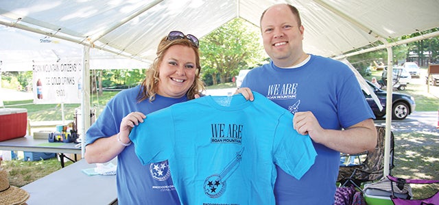 Star Photo/Curtis Carden  Roan Mountain Citizens Club president Brian Tipton, right, and member Shellie McKinney present one the 70th annual Rhododendron Festival shirts. on sale Sunday. Tipton designed this year's logo.